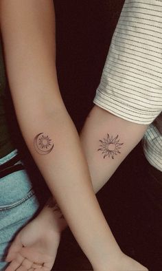 two people are holding hands with tattoos on their arms and one has a sun and moon