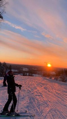 a person riding skis on top of a snow covered slope in the sun setting