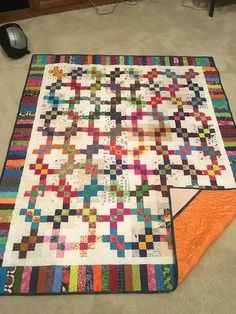 a multicolored quilt is laying on the floor next to a computer mouse and keyboard