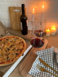 a pizza sitting on top of a wooden cutting board next to a glass of wine