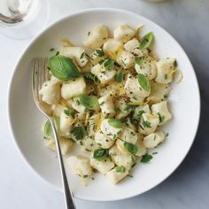 a white plate topped with pasta and garnished with herbs