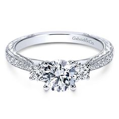 a white gold engagement ring with three diamonds on the side and an intricate band around it