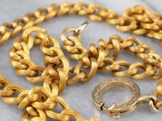 Another stunning Victorian-era piece! This antique chain necklace is crafted of 18 karat yellow gold in the distinctive style of the early 1900's Victorian era. Each of the links is grooved, with rope twist details, finished with an oversized engraved clasp. The workmanship is exquisite, and the condition is excellent, especially considering the great age of the necklace. Metal: 18K Yellow Gold Width of Chain: 7.7 mm Length of Chain: 21 Inches To view a video of this piece check out the link bel Luxury Antique Link Chain Necklace, Heirloom Yellow Gold Chain Necklace, Formal Rope Chain Necklace, Gold Engraved Oval Link Chain Necklace, Antique Yellow Gold Link Necklace, Antique Style Oval Link Chain Necklace, Vintage Gold-tone Oval Link Necklace, Formal Engraved Gold Chain Necklace, Heirloom Link Necklace For Formal Occasions