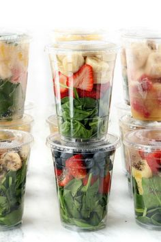 several plastic cups filled with different types of fruit and veggie salads on top of each other