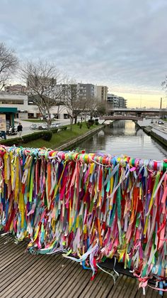 colorful streamers hanging on the side of a wooden pier next to a body of water