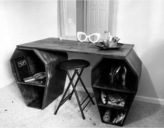 a black and white photo of a desk with two stools next to it on the floor