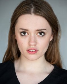 a woman with brown hair and blue eyes looks at the camera while wearing a black shirt