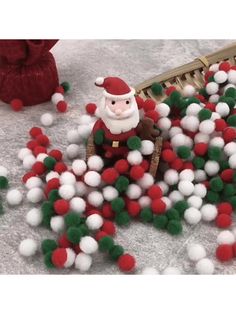 a santa clause sitting in a pile of pom - poms next to a basket