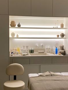 a white bed sitting next to a bathroom sink under a mirror in a room with shelves above it