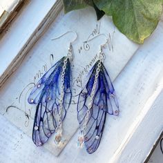 Our very pretty purple faerie wing earrings which are just perfect for any faerie! We make the wings ourselves and they are made from a type of plastic and magic, oh and a sprinkle of glitter of course! The two wings are separate which help create movement Finished with the best quality crystals and a pretty crystal drop, which catches the light perfectly! We make the wings ourselves and they are made from a type of plastic and magic, oh and a sprinkle of glitter of course! The two wings are separate which help create movement. We offer these earrings in sliver plated and bronze plated nickel free earring hooks Please note that no faeries have been harmed in the making of these wings! Villainous Outfits, Vibey Jewelry, Blue Fairy Jewelry For Party, Blue Fairy-style Jewelry For Party, Purple Fairycore Jewelry For Party, Knight Cookie, Tvd Dr, Wing Jewelry, Fairy Jewelry