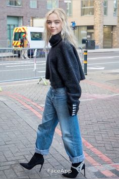 a woman is walking down the street wearing high heels and a black turtle neck sweater