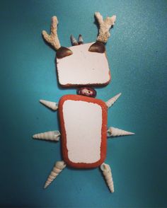 an animal made out of clay sitting on top of a blue surface with white and red decorations