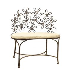 a metal bench with a cushion on it's back and flower design above the seat