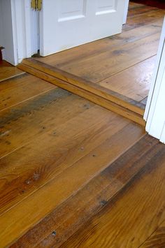 an open door on the side of a wooden floor next to a pair of white doors