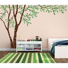 a bedroom with a tree painted on the wall and a green rug in front of it