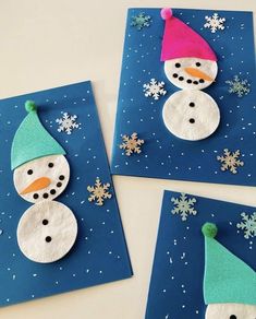 three snowmen made out of felt sitting on top of blue paper