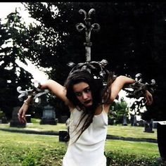 a woman with her arms outstretched in front of a cross and headdress on