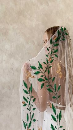 a woman wearing a veil with flowers and leaves painted on the back of her head