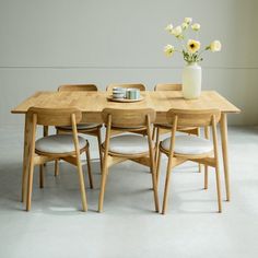 a wooden table with four chairs and a vase filled with flowers on top of it