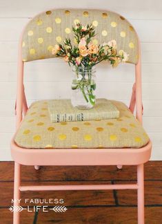 a pink chair with flowers in a vase on it