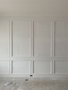 an empty room with white paneling on the walls