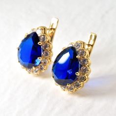 Gold Sapphire Earrings set with Created Sapphire in a flawless clarity, pear diamond cut & stunning royal blue color, at 16x12mm each surrounded with Created CZ Diamonds at 3mm each (22 Cts a pair) Gold Vermeil: 18k Gold over Solid 925 Sterling Silver ☞ made to last. Matching Pendant: www.etsy.com/listing/958926549 Matching Ring: www.etsy.com/listing/780193095 For Pierced Ears - has a pin that goes into the ear and a leaver that securely closes on the pin behind the earlobes - "English Lock" Details : ♥ Each item comes in a cute GIFT BOX ✓ ♥ GUARANTEE on all materials ✓ ♥ Created Sapphire in a flawless clarity & CZ Diamonds ✓ ♥ 18k Gold over Solid 925 Sterling Silver ✓ ♥ Measurements: Sapphire size 16x12mm each & CZ Diamonds at 3mm each, 22 Carats a pair✓ ♥ Each stone set professionally - Diana Earrings, Large Statement Earrings, Matching Ring, Cute Gift Boxes, Royal Blue Color, Matching Rings, Pear Diamond, Sapphire Earrings, Earrings Blue