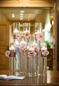 there are many tall vases with flowers in them on the table and one is filled with candles