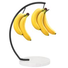 two bunches of bananas are hanging from a black metal stand on a white surface