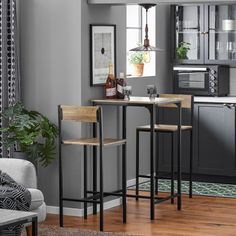 a kitchen with grey walls and wooden flooring, bar stools in front of the counter