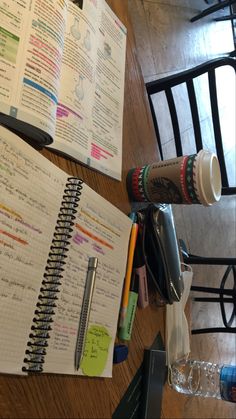 a wooden table topped with notebooks next to a bottle of water and a pen