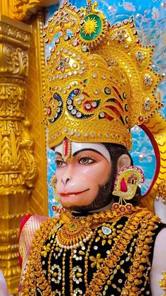 a monkey dressed in gold and wearing a headdress with jewels on it's face