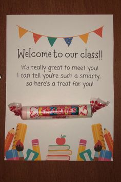 a candy bar sign is displayed on a wooden table with an apple and school supplies