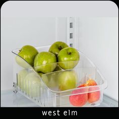 there are many green apples in the plastic container on the shelf next to each other