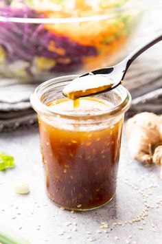 a spoon full of sauce sitting on top of a table next to garlic and ginger