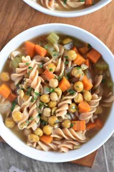 two bowls filled with pasta and vegetables on top of a wooden table next to each other