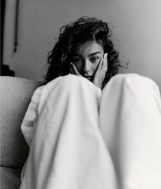 a black and white photo of a woman laying in bed talking on her cell phone