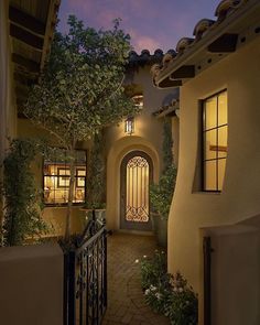 an entrance to a home at night with lights on and trees in the foreground