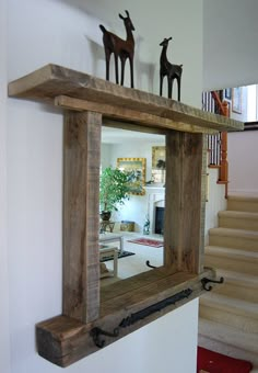 a mirror that is hanging on the wall in front of a stair case with two deer figurines