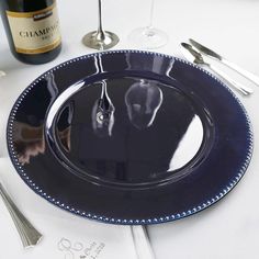 there is a blue plate on the table with silverware and wine glasses next to it