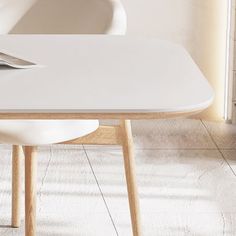 a laptop computer sitting on top of a white table next to a chair and window