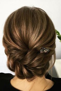 the back of a woman's head with her hair in a low bun and two pins