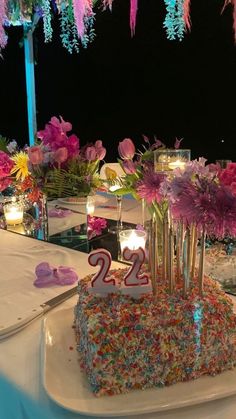 a birthday cake with candles and flowers on the table at a 21st birthday party or celebration