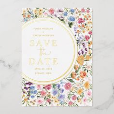 a floral save the date card with gold foil on it and white marble background, featuring flowers