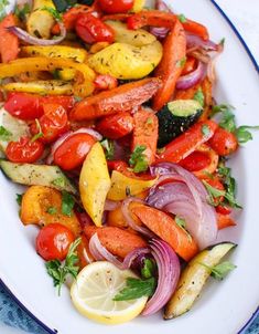 a white plate topped with lots of different types of veggies and lemon wedges