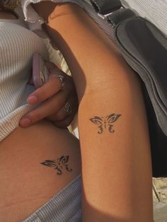 two women with tattoos on their legs and one has a cell phone in her hand