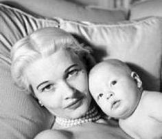 a woman laying on top of a bed holding a baby