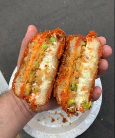 a person holding two pieces of food in their hand on a paper plate with the other half eaten