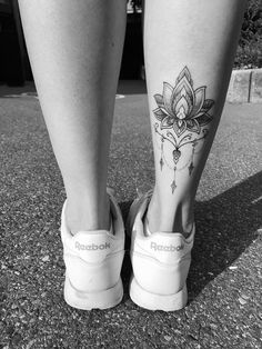 black and white photo of woman's legs with lotus tattoo