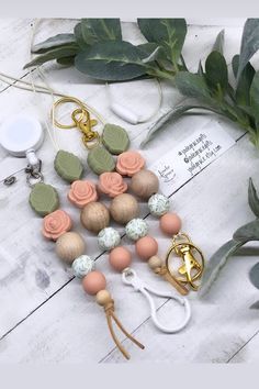 several wooden beads, scissors and other items on a white wood table with eucalyptus leaves