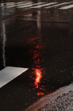 a red light shines on the wet ground as it is reflected in puddles